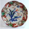 Companhia das Índias; Raro prato em pasta dura de porcelana, decorado no “Padrão IMARI/Chinese Imari”, com borda recortada. Sua decoração traz motivos da flora e fauna japonesa e rica policromia com fundo branco e pinturas em esmalte, predominando as cores azul índigo e rouge de fer, apresentando resquícios de ouro em sua volta. Séc. XVIII/ XIX. Diâmetro 19 cm. (Pequeno bicado na borda). 