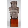 <p>Escultura oriental, representando cabeça de Buda, de pedra, sobre base de madeira - 50 cm alt com a base - séc XIX</p>