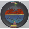 <p>A imagem apresenta um prato de cerâmica criado por Megumi Yuasa, um escultor e ceramista nipo-brasileiro nascido em São Paulo em 1938. A peça exibe um design abstrato e cores vibrantes sobre um fundo preto fosco. O prato parece ser feito de cerâmica de alta temperatura e revestido com pigmentos naturais.</p>