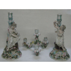 Dois belíssimos castiçais em porcelana alema, policromada, marca da manufatura Sitzendorf, tendo como destaque figura feminina com representação de alegria e tristeza. Decorados com flores e trabalhos em relevo. Um deles pode ser usado como candelabro para 5 velas. (a parte de cima do candelabro apresenta restauro e a gaiola e algumas flores com pequenas quebras). Alt. castiçal 34,5cm e Alt. candelabro 49,5cm. 
