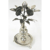 Paliteiro em prata, na forma de vaso com ramo de flores, folhas e frutos. Base circular, com pés em garra. Alt. 21,5cm. Peso 425g.