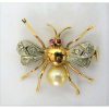 Delicado e elegante broche, em ouro 18K, amarelo e branco, na forma de abelha. Peça cravejada com pequenos brilhantes e pérola. Peso 3,6g. (Este ítem não se encontra no local da exposição).