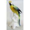 Papagaio de coleção Art-deco, em porcelana alemã, marca da manufatura - Volkstedt, da fábrica Karl ENS, policromada, estando este sobre galho com flores e folhas. Alt. 25cm.