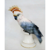 Bela escultura de coleção, em porcelana alemã policromada, época Art-deco, representando Cacatua. Peça com finos detalhes, decorada com frisos em dourado na base. Marca da manufatura Passau (incorporada posteriormente à Volkstedt). Alt. 26cm. 