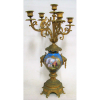 Belo candelabro francês, possivelmente Sévres, para 6 velas, em porcelana e bronze ormulú, sendo a porcelana na cor azul, decorada com pintura em policromia de cena musical e flores. Detalhes em dourado. Bronze finamente trabalhado com cinzelados e guilhochados com cabeças de leão a guisa de alças. Alt. 54,5cm. 