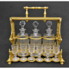 Belo e elegante tantalus francês, com marca da Cristallerie Baccarat, em bronze ormulú, composto por 3 licoreiros e 12 tacinhas em cristal translúcido, lapidado em facetados e frisos (um licoreiro com 2 fissuras internas que não deixam vazar o líquido). Marca da Cristallerie em crivo no bronze. Com chave original e funcionando. Med. tankard 29,5x28,5x18,5cm. 