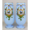 Belíssimo e elegante par de vasos em opalina européia, do Séc. XIX, possivelmente Baccarat, no tom azul, decorados com pinturas em policromia e toques esmaltados, de flores, folhagens e laço, tendo em reserva borboleta. Detalhes em dourado. Alt. 30cm.