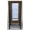 Vitrine em madeira nobre entalhada, estilo inglesa, porta e laterais em vidro, interior com 4 prateleiras de alturas reguláveis, espelho no fundo e na base. Apresenta entalhes em folhas. Sustentada por 4 pernas torneadas com trabalhos em espiral. Med. 155x70x47cm.