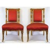 Par de elegantes cadeiras baixas, estilo francês, em madeira dourada e entalhada. Assentos e encostos forrados em tecido no tom vinho. Med. 75x47x 48 cm.