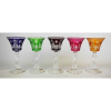 Belo e elegante conjunto de 5 tacinhas em fino cristal europeu, sendo uma de cada tonalidade, profusamente lapidadas em estrelas, frisos bisotados, olivas e folhagens. Haste central sextavada com lapidações serrilhadas. Base com estrela. Alts. 12,5cm.