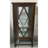 Vitrine em madeira nobre entalhada com influência do estilo Manoelino, formada por porta de abrir com vidros bisotados. Laterais em vidros bisotados. Interior com 4 prateleiras de alturas reguláveis, fundo e base com espelhos. Pernas em elos unidos por travessões. Med. 150x68,5x43,5cm.