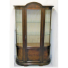Bela vitrine em madeira entalhada, laterais bombé e porta central com vidros. Interior com 4 prateleiras, sendo duas inferiores em madeiras e duas superiores em vidro. Fundo forrado em tecido. Med. 1,95x1,19x40cm.