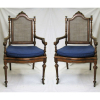 Par de cadeiras de braços, estilo francês Luis XVI, do séc. XIX, em jacarandá entalhado. Assento e encosto em palhinha com rodinhas. Assento de uma com palhinha no estado. Med. 111x59x51cm.