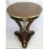 Bela mesa de apoio, estilo Império, em madeira nobre trabalhada com marqueterie. Tampo circular sustentado por 3 pernas recurvas unidas por platô inferior. Apliques e guarnições em bronze trabalhados com carátides, flores e folhagens. Med. 76x57x57cm.