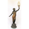 Grande luminária de chão em petit bronze representando Jovem sustentando tocha, com vestes patinadas de dourado. Cúpula em vidro com trabalhos em forma de chamas de fogo. Alt. 156,5cm.