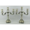 Par de candelabros em prata contrastada, com marca do teor 833 milésimos, decorados com trabalhos de folhas e volutas em relevo. Um apresenta mossa na base. Alts. 31,5cm. Peso 2.260g.