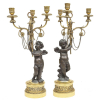 Belíssimo par de candelabros franceses, em bronze, em dois tons, para 3 velas, sustentado por figura de meninos anjos. Braços dos candelabros e base dourados com flores e folhas. Alt. 55cm.