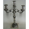 Candelabro brasonado, para 4 velas, em prata européia, contrastada e cinzelada em flores, círculos, folhagens e volutas. Base com pequeno amassado. Alt. 47cm. Peso 1.435kg.