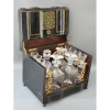 <p>CAVE A LIQUEUR, NAPOLEON III, FRANCE C. 1850. Caixa em madeira ebanizada e marchetada, encustração de lâminas de metal dourado. Quatro licoreiros, dezesseis taças. Três tampas idênticas e uma tampa diferenciada- *Consta rachadura. Medidas: 27 x 33 x 24 cm. Medidas aberta: 45 x 64 x 26,5 cm. Taças: 7 x 4 x 4 cm. Licoreiras: 20 x 7,5 x 7,5 cm. O PERÍODO (1852-1871) Charles-Louis Napoléon Bonaparte era o terceiro filho de Louis Bonaparte , o rei da Holanda e irmão mais novo de Napoleão , e Hortense de Beauharnais , filha da Imperatriz Josefina , e se tornou o herdeiro da família imperial após a morte de seus dois irmãos mais velhos em 1807 e 1821. Imperador dos franceses de 1851 a 1870 Após uma juventude turbulenta e várias tentativas de tomar o poder durante a monarquia de julho , foi eleito presidente da Segunda República Francesa em 1848. Ele transformou sua presidência em um título imperial graças a um golpe em 2 de dezembro de 1851, autoproclamando-se Napoleão III, imperador dos franceses. O novo regime foi totalmente napoleônico e renovou a glória militar e a ostentação passadas na França, e também foi um período de grande prosperidade econômica. O ESTILO: Um princípio básico da decoração interior de Napoleão III era não deixar nenhum espaço sem decoração. Outro princípio era a policromia , uma abundância de cores obtida pelo uso de mármore colorido, malaquita , ônix , pórfiro , mosaicos e bronze folheado a prata ou ouro. Os painéis de madeira costumavam ser incrustados com madeiras raras e exóticas ou escurecidos para se assemelhar ao ébano . A fachada da Opéra Garnier empregava dezessete materiais de cores diferentes, incluindo vários mármores, pedras e bronze.</p>