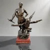 “LE GÉNIE DES NATIONS” — LUCA MADRASSI (1848-1919)<br />Bronze maciço com pátina marrom | Selo de fundição “AB – PARIS”<br />Escultura: 81 x 59 x 57 cm | Base mármore rouge: 9 x 33 x 33 cm<br />Altura total: 90 cm | Peso: 71,5 kg | França, c. 1890-1900<br /><br />Monumental grupo escultórico em bronze de Luca Madrassi, titulado “Le Génie des Nations”, fundido em Paris, c. 1890-1900. Jovem alado em pé, nu, com espada na mão direita, protege figura feminina alada que avança com tocha e braço estendido — alegoria da Liberdade guiando o Gênio da Civilização. Assentado sobre rocha naturalista com pergaminhos inscritos “DROIT DES NATIONS”. Base em mármore vermelho Griotte. Selo “AB PARIS” na base — Fundição A.B. / A. Barbedienne ou A. Blanchard, as mais prestigiadas de Paris.<br /><br />Artista: Luca Madrassi (Tricesimo 1848 – Paris 1919)<br />Italiano naturalizado francês, Madrassi estudou na Académie de France em Roma e foi discípulo de Carrier-Belleuse. Expôs no Salon des Artistes Français de 1879 a 1914 e recebeu medalha de ouro na Exposition Universelle de 1900, Paris — a mesma que você citou. Especializou-se em grupos alegóricos monumentais para salões e edifícios públicos. “Le Génie des Nations” é sua obra mais emblemática, símbolo da paz armada da Belle Époque.<br /><br />Fundição: AB – PARIS<br />O selo “AB PARIS” corresponde à Fonderie A.B. Ateliers Barbedienne, fundições que trabalhavam com os grandes escultores do Salon. Madrassi editava quase toda sua obra na Susse Frères e Barbedienne. A pátina marrom sombreada, típica de Barbedienne, e os 71,5 kg de bronze maciço confirmam edição de luxo, não bronze de série.<br /><br />3. História e tipologia<br />Apresentado em gesso no Salon de 1898 e em bronze na Universal de 1900, “Le Génie des Nations” celebra o Direito Internacional e a proteção das Artes e Ciências pela Força. O gênio alado masculino — a Nação armada — guarda a Liberdade que leva o facho do Progresso. É a retórica da III República Francesa em bronze: pacifista, mas pronta para a guerra.<br /><br />Em 2019, a Bonhams vendeu “Le Génie des Nations”, 84 cm, por £ 32.000. Com 90 cm, 71,5 kg, mármore e selo AB,