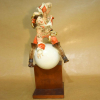 MEISSEN - Figura satírica de BARÃO MUNCHHAUSEN, marcado em baixo relevo A. STRUCK. Altura:39 cm. <br />Wearing a frock coat, iron-red breeches and boots, modelled holding his tricorn hat and riding the moon, on a stepped ebonised wooden base<br />14 in. (35.5 cm.) high <br />Peso:2.700 g. Medidas: 39 x 20 x 25 cm.<br />https://www.meissen.com/en/catalog/category/view/s/alexander-struck/id/989/<br />*Pé com restauro<br /><br />Karl Friedrich Hieronymus von Münchhausen, Os relatos de suas aventuras serviram de base para a célebre série As Aventuras do Barão de Münchhausen, compiladas por Rudolph Erich Raspe e publicadas em Londres em 1785. São histórias fantásticas e bastante exageradas, propagadas sobretudo na literatura juvenil. Um personagem que se equilibra entre a realidade e a fantasia em seu mundo próprio, onde enfrenta os mais diversos perigos, perpetra fugas impossíveis (sendo a mais famosa delas: a fuga do pântano do qual afundara junto com seu cavalo, tendo conseguido escapar ao puxar a própria peruca), testemunha fatos extraordinários e faz viagens fantásticas — sem jamais perder a fleuma.<br /><br />A Peça Traz a Representação de uma de suas Histórias fantásticas, Onde ele conta a todos como foi seu triunfo em batalha, quando uma bola de canhão disparada por acidente e o lança aos ares, de onde pôde ver do alto todo o exército inimigo e retornar à seu forte voando em outra bola de Canhão que vinha de encontro. <br /><br />As Histórias Fantásticas inspiraram o nome de distúrbios médicos relacionados à mentirosos Compulsivos, caracterizados pelo extremo exagero.