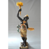 BLACKAMOOR VENEZIANO<br />Escultura em madeira talhada, carnada e policromada.<br />Folhas de ouro. Bandeja numa mão, e tocha na destra.<br />No estado.<br />Medidas: 216 x 52 x 52 cm. Só a base: 67 cm<br /><br />REFERÊNCIAS: Imensamente popular do século 16 ao 19, o estilo “BLACKAMOOR” apresentava figuras africanas estilizadas e era comum em esculturas, joias e móveis. <br />Pintadas em esmalte preto brilhante e enfeitadas com trajes de penas coloridas, teriam funcionado como uma forma palatável de exotismo para seus proprietários europeus brancos, imitando os servos e escravos negros vestidos de forma teatral que faziam parte das casas nobres europeias. No entanto, essas figuras negras primorosamente modeladas também foram lidas como uma homenagem ao triunfo colonial da Europa. Essas estatuetas de porcelana muitas vezes continham tigelas de açúcar, dado o uso de mão-de-obra escrava negra nas plantações de açúcar dos primeiros europeus modernos. <br />Derivado da palavra latina “Maurus”, o termo foi originalmente usado para descrever os berberes e outras pessoas da antiga província romana da Mauritânia, onde hoje é o Norte da África. Com o tempo, foi cada vez mais aplicado aos muçulmanos que viviam na Europa. A partir da Renascença, “mouro” e “BLACKAMOOR” também eram usados para descrever qualquer pessoa de pele escura.<br /><br /><br />