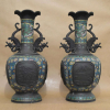 PAR DE VASOS em BRONZE e CLOISONEÉ . CHINA - Dinastia Qing (1644 a 1912)<br />Duas reservas figurando, vulcão e Salgueiro chorão. Bojo em flores miúdas, Aves do Paraíso no pescoço. Alça DRAGÕES ALADOS.<br />61X32X32 CM.<br /><br />A ARTE DA ESMALTAGEM:<br />CLOISONNÉ - Do francês CLOISON: divisão, célula, favo.<br />Técnica de esmaltagem, LIMITADA por finas tiras de metal soldadas sobre uma superfície, afim de formar meticuloso desenho composto por vários compartimentos, favos ou CLOISONSpreenchidos com pasta de esmalte vitrificado, levados a fornos em altíssima temperatura e polidos até atingirem o acabamento ideal.<br />Os exemplares mais antigos conhecidos são provenientes de Chipre, do séc. XIII a.C., mas foi no império bizantino que se desenvolveu grandemente esta arte, a partir <br />dos séculos IX, X da nossa era.<br />Assista o Video:<br />https://www.youtube.com/watch?v=b1NLJw5kfgQ<br />