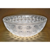 LALIQUE FRANCE - ART GLASS - c.1929<br />CRYSTAL LARGE 10 <br />NEMOURS BOWL (A CIDADE DE NEMOURS ERA CONHECIDA POR SEUS DOCES DE PAPOULA, E O DESENHO EXTERNO DA TIGELA É UMA MULTIDÃO GEOMÉTRICA DE FLORES DE PAPOULACOM UM PONTO PRETO NA PARTE INFERIOR DE CADA UM.<br />10X25,5X25 cm.<br /><br />Nascido René Jules Lalique em 1860, no pequeno vilarejo de Ay, na região de Marne na França (antiga província de Champagne), René Lalique chegaria ao topo de muitos campos antes que sua longa carreira terminasse com sua morte em 1945.<br />René Lalique nasceu um homem rural do século 19 em uma Europa pré-industrializada. Foi uma época antes das lâmpadas e dos telefones, antes dos automóveis, das máquinas de lavar e da eletricidade. Mas na época de sua morte em 1945, no alvorecer da era atômica, ele teria completado duas carreiras em dois séculos diferentes. Em 1900, aos 40 anos, era o joalheiro mais famoso do mundo e um artista e designer art nouveau de magníficas proporções. Mas em 1925, no auge da era art déco, ele era o vidreiro mais famoso do mundo. No meio tempo, Lalique deixaria seus contemporâneos para trás enquanto deixava de criar joias e objetos de arte exclusivos para a produção em massa de vidro de arte inovador e utilizável. Ele trouxe o vidro para a casa das pessoas comuns, onde nunca tinha estado antes,<br /><br />Lalique é lembrado por suas joias e seu copo. Mas suas maiores realizações nasceram em seu reconhecimento do mundo em mudança em que vivia. Sua vida abrangeu todo o período da Guerra Civil à Segunda Guerra Mundial e, conforme seu mundo mudou, Lalique também mudou. Sua incrível virada de carreiras e campos o colocou na vanguarda da nova produção em massa. Ele era um joalheiro, ele era um vidreiro, ele era um artista. Mas sua grande conquista foi combinar esses talentos com visão e inovação não apenas para atender aos mercados, mas também para criá-los. No processo, Lalique se tornaria um industrial de classe mundial com uma habilidade industrial equivalente a qualquer outro de seus ricos talentos e realizações.<br /><br />O artista, o designer, o joalheiro, o inovador, o vidreiro, o industrial, o visionário! Esta é a história dele.