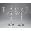 Par de candelabros para três velas de prata repuxada, braços recurvos em linha, sobre coluna canelada, base ovalada. 43 cm de altura. Contraste águia para a prata do Porto de teor 833, em uso a partir de 1938 e do prateiro José Ferreira Azevedo, registrada em 1936.