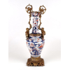 <p>Belíssimo e grande vaso de porcelana padrão Imari, decorado com motivos florais em azul e Rouge de Fer. Exuberantes alças em bronze - Ormolu, fundido em representações Angelicais em alegoria mitológica subaquáticas, empulhando folhas de acanto fundidas e retorcidas com volutas, conectados por virola. Séc. XVIII - 70 cm alt. (Peça com restauro)</p>