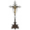 <p>Crucifixo D. João V com Imagem de Cristo em madeira esculpida, policromada e modelada de forma naturalista, e dourado. Cabelos longos e movimentados, mandorla de ouro com ametista no centro, chagas com filetes escorridos em vermelho, perizôneo entalhado, dourado e movimentado, com dobras e drapeados; pés, o direito sobre o esquerdo e mãos, presos por cravos de prata, também com ametistas no centro. Cruz de jacarandá envernizado com rebaixos laterais filetados, ornada com raionados, ponteiras, duas placas de contornos irregulares com volutas, de prata, centralizando à Imagem, sendo: uma retangular com inscrição JNRJ (Jesus de Nazaré Rei dos Judeus) e outra ovalada com reserva central lisa, de prata. O todo sobre imponente base semicircular escalonada e movimentada, com facetas ligeiramente côncavas e concêntricas, sobre três pés curvos; 51 cm de largura e 114 cm de altura total. Brasil, séc. XVIII.  Pertenceu à Capela do engenho de São Miguel de Cotegipe, próximo à Salvador, BA, da família Alves de Lima Costa.</p>