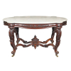 Mesa de centro estilo Império em jacarandá - tampo de mármore de Carrara com quebras onduladas nas extremidades acompanhando o aro da mesa - decorada em todos os lados com ramagens e flores entalhadas - assenta sobre quatro pernas encurvadas recobertas com folhas entalhadas, todas com rodízios - travejamento em X ondulado, tendo ao centro uma pinha entalhada - 160 x 100 x 90 cm - Brasil/Bahia, séc. XIX